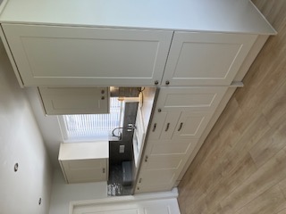 Fitted shaker kitchen with tall larder unit and light oak laminate flooring